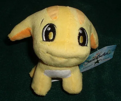 A yellow Poogle plush from Neopets with big black eyes, orange-tipped ears, and a white belly patch, sitting on dark green fabric with an official limited-edition tag attached.